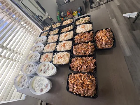 Rows of prepared meals, rice trays and bowls on a dining table.