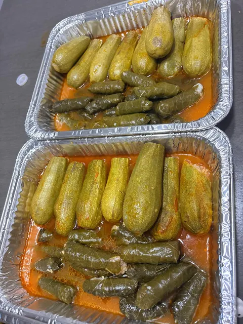 Two foil trays filled with stuffed zucchini and grape leaves.