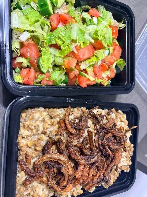 Individual containers of fresh salad and rice with lentils and browned onions.