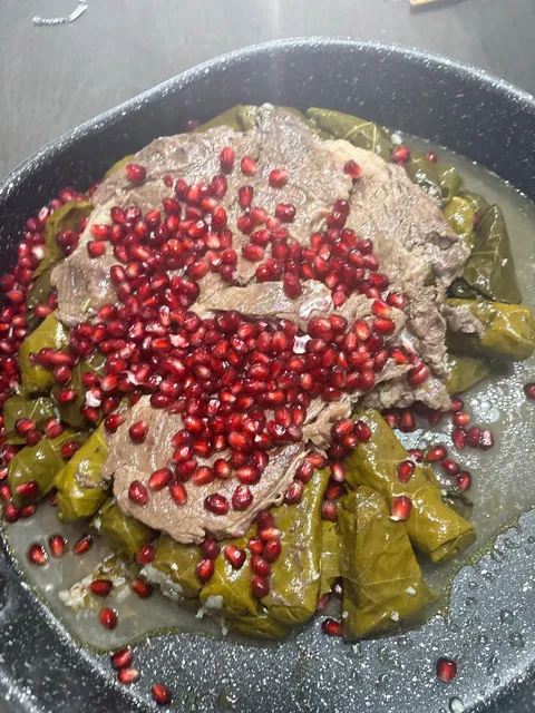 A pot of stuffed vegetables topped with meat and pomegranate seeds.