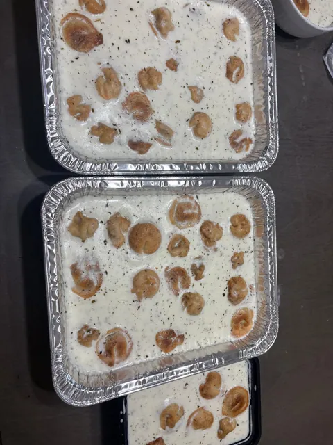 Two foil trays of a creamy white dish with decorative brown toppings.