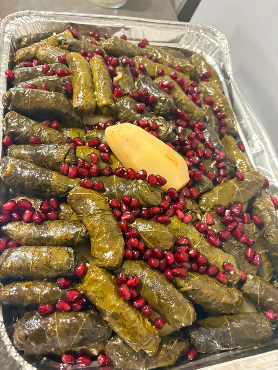 A tray of grape leaves garnished with pomegranate and lemon.
