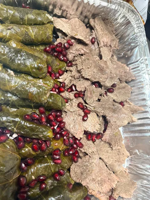 A close view of grape leaves and pieces of meat in a family tray.