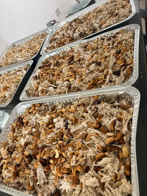 Several foil trays of rice topped with meat and browned onions.