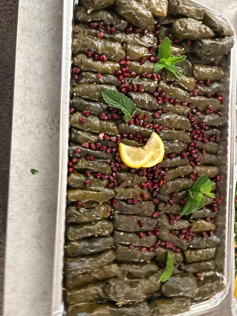 A long foil tray of grape leaves finished with lemon and pomegranate.