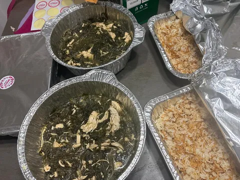 Bowls of cooked greens beside a family tray of rice.