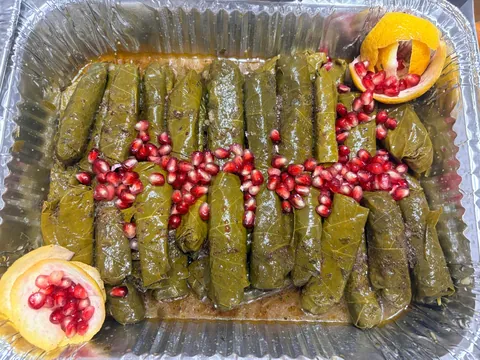 Stuffed zucchini and grape leaves garnished with lemon and pomegranate seeds.