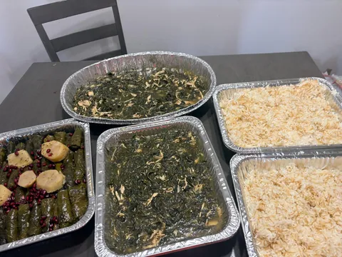 Several family trays of greens, rice and stuffed grape leaves.