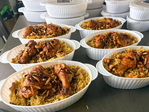 Individual white dishes filled with chicken and golden rice.
