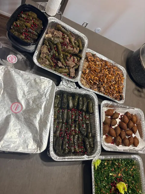 A table of stuffed grape leaves, salad, rice and other prepared dishes.