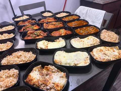 Rows of individual meals with rice, roasted dishes and baked toppings.