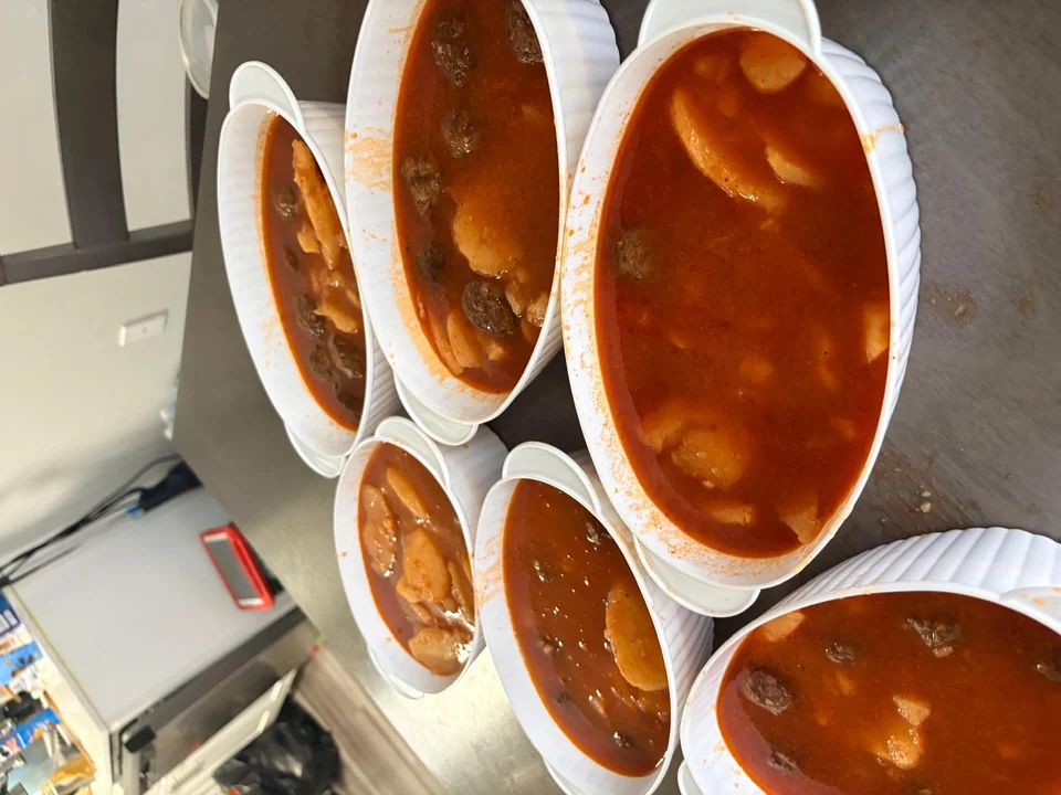 Several white bowls filled with a red stew and vegetables.