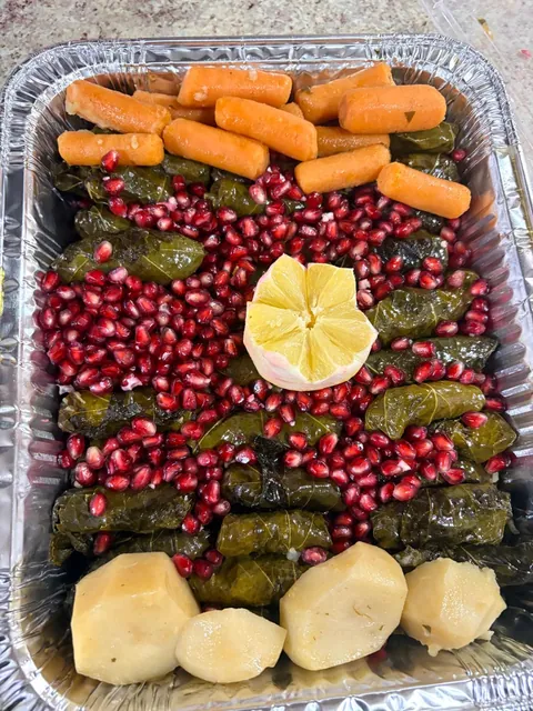 A tray of grape leaves with carrots, potatoes, lemon and pomegranate.