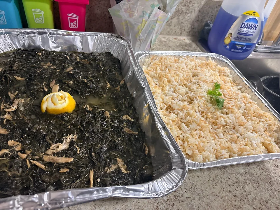 Large family trays of cooked greens and rice.