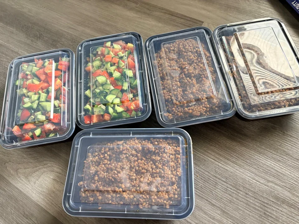 Prepared family trays with fresh salads and rice dishes, some with lids.