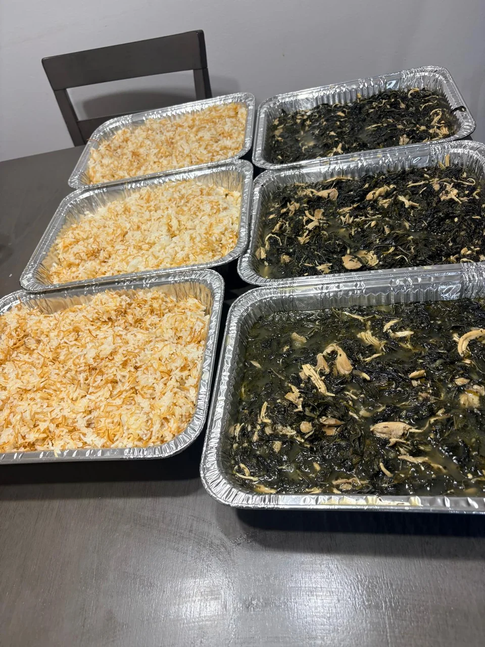 Large trays of cooked greens and fluffy rice ready for a gathering.